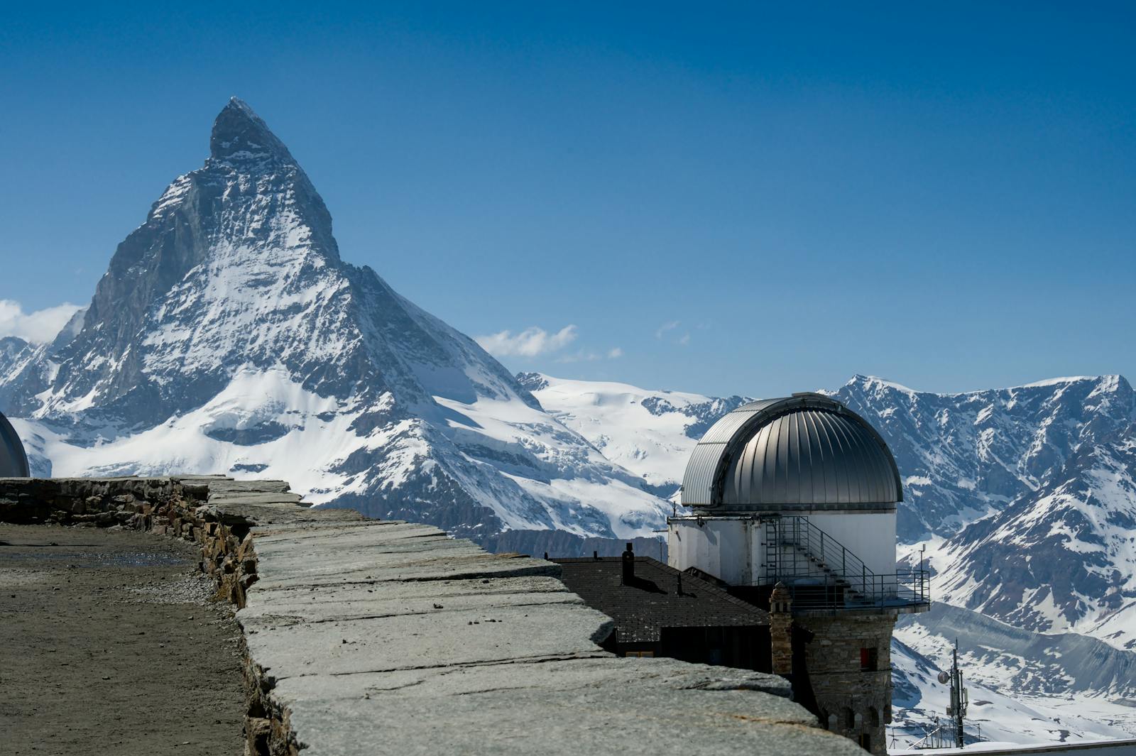 Snow-covered Matterhorn with Gornergrat observatory under a clear blue sky.